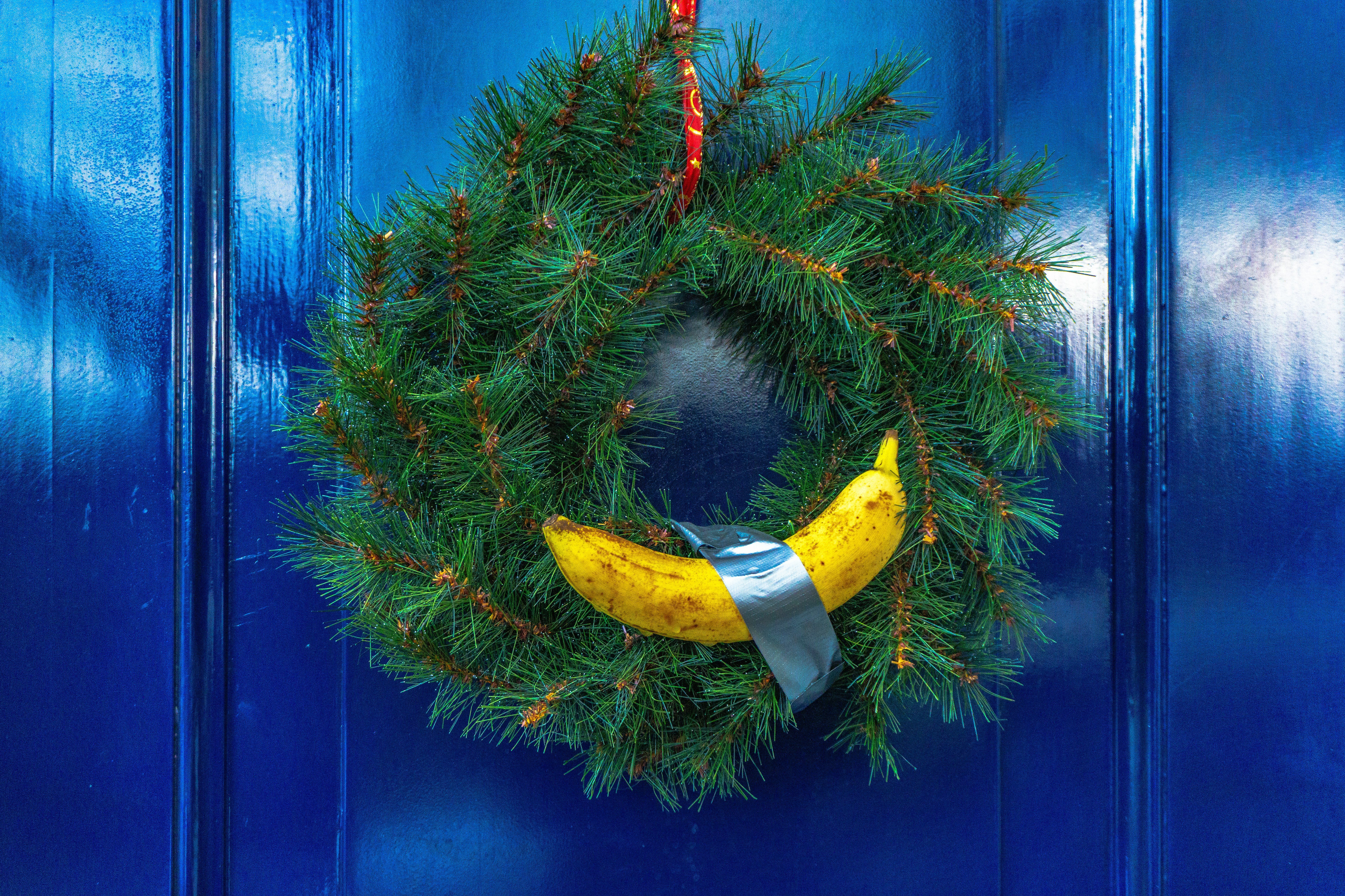 green spruce wreath with yellow banana hanging on a blue door